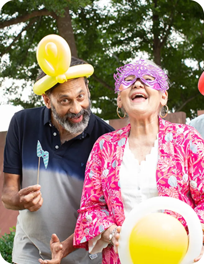 An elderly couple celebrating with balloons